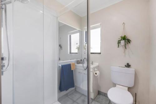 a white bathroom with a toilet and a shower at Logan House, Stylish Getaway With BBQ and Yard in Taupo