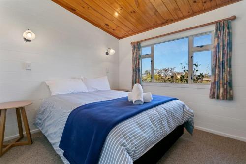 ein Schlafzimmer mit einem Bett und einem Fenster in der Unterkunft Bellbird Cottage With Lake and Mountain Views in Taupo
