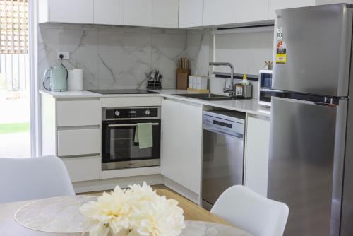 a kitchen with white appliances and a table with chairs at Brand New Backyard Guest House in Werribee CBD in Werribee