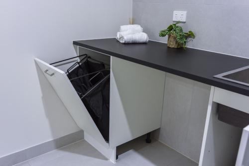 a kitchen with a black counter top and a dishwasher at Brand New Backyard Guest House in Werribee CBD in Werribee