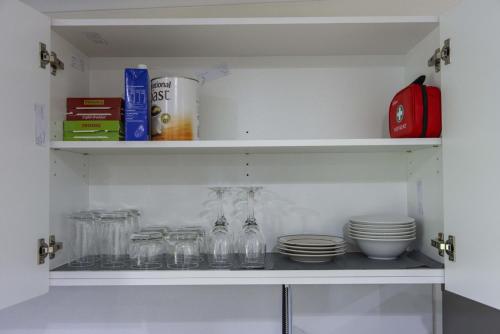 a shelf with dishes and glass jars and plates at Brand New Backyard Guest House in Werribee CBD in Werribee
