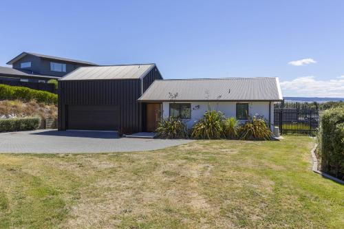 a black and white house with a yard at Elevated Taupo Hideaway With Views and Designer Comfort in Taupo