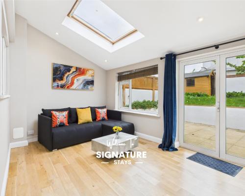 a living room with a black couch and a skylight at Queens Road by Signature Stays - Modern - Central in Cheltenham
