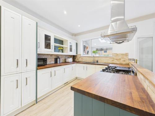 a kitchen with white cabinets and a wooden counter top at Queens Road by Signature Stays - Modern - Central in Cheltenham