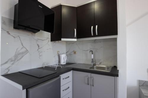a kitchen with black cabinets and a sink at NMS Apartments in Ksamil