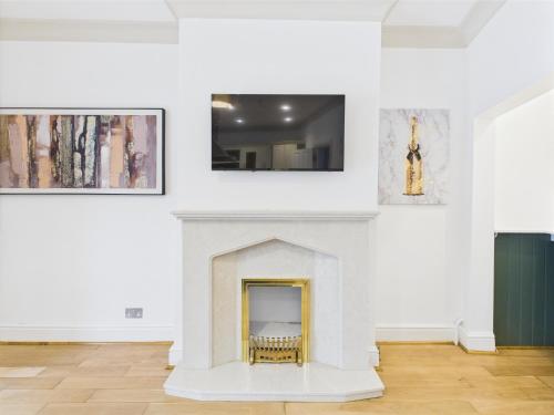 a room with a fireplace and paintings on the wall at Queens Road by Signature Stays - Modern - Central in Cheltenham