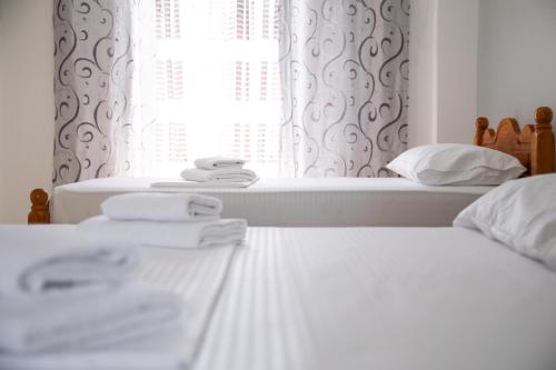 two beds in a bedroom with white sheets and a window at NMS Apartments in Ksamil