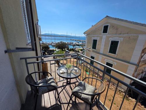 a balcony with three chairs and a table on a balcony at Apartment Neo in Malinska