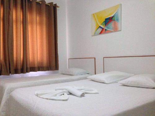 two beds in a room with white towels on them at Hotel Miranelli in Barbacena