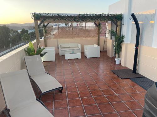 a patio with a pergola and chairs on a balcony at Basement apartments in San Bartolomé de Tirajana
