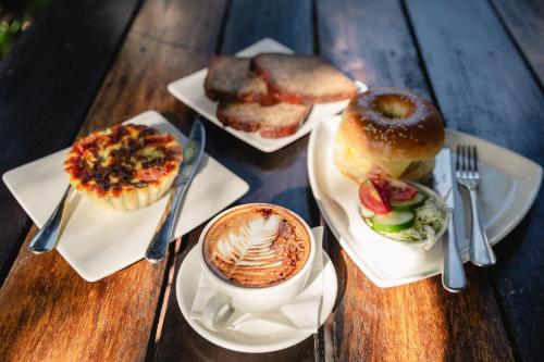 a table with three plates of food and a cup of coffee at The Shady Rest Hotel in Port Moresby