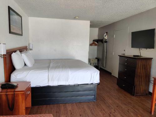 a hotel room with a bed and a television at Travelodge Suites by Wyndham MacClenny I-10 in Macclenny