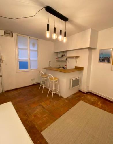 - une cuisine avec un comptoir et des chaises dans la chambre dans l'établissement Studio 9 Trinité - Hypercentre Toulouse, Accueil H24 et Wi-Fi, à Toulouse