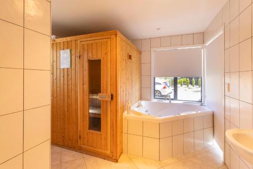 a bathroom with a tub and a window and a sink at Wanaka Retreat Spa, Sauna & Mountain Views in Wanaka