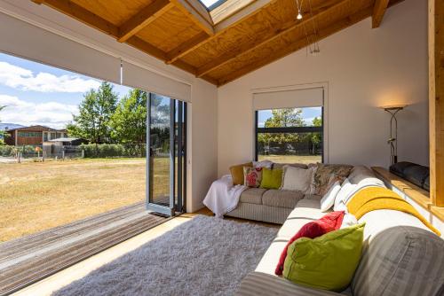 a living room with a couch and a large window at Wanaka Retreat Spa, Sauna & Mountain Views in Wanaka