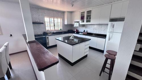 uma cozinha branca com uma pia e uma geladeira em Casa Campos do Jordão em Campos de Jordão