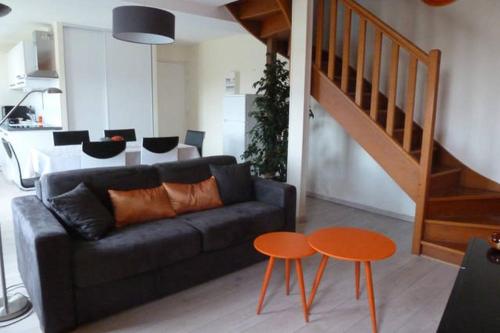 a living room with a black couch and two orange tables at Le Clos Saint Martin in Laon