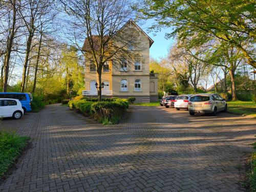 a house with cars parked in a parking lot at Emily's Deichbude in einer historischen Villa in Dornumersiel in Dornum