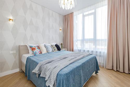 a bedroom with a bed with a blue blanket and a window at Теплый уголок Aruna City in Astana