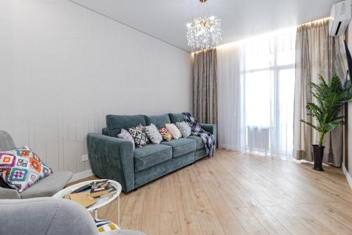 a living room with a green couch and a large window at Теплый уголок Aruna City in Astana