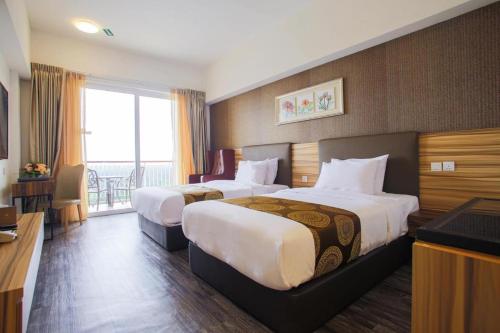 Una habitación de hotel con dos camas y balcón. en Residenz Apartments in Amerald Resort Hotel Desaru, en Desaru