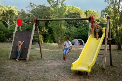 two boys playing on a slide at a park at Camping U STABIACCIU in Porto-Vecchio