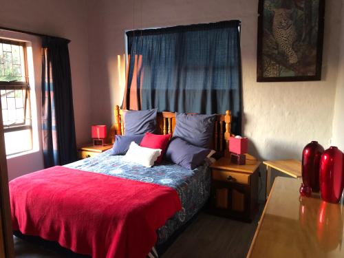 a bedroom with a large bed with a red blanket at All the Way in Hartbeespoort