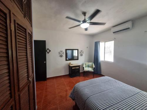 a bedroom with a bed and a ceiling fan at Casa Columpios, con alberca a pasos de la playa in Chuburná