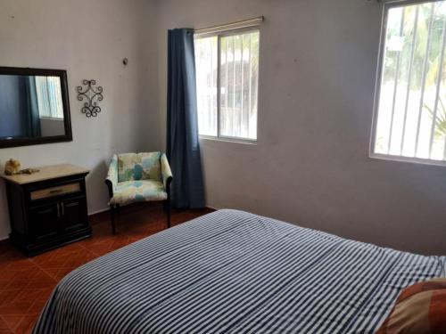 a bedroom with a bed and a tv and a chair at Casa Columpios, con alberca a pasos de la playa in Chuburná