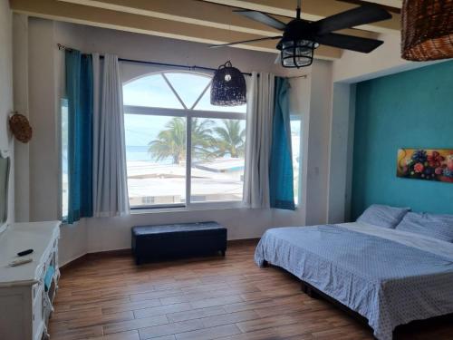 a bedroom with a bed and a large window with the beach at Casa Columpios, con alberca a pasos de la playa in Chuburná