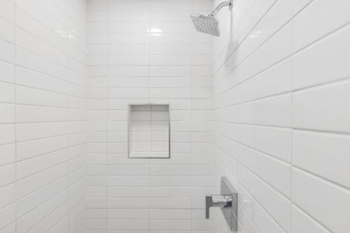 a white tiled bathroom with a shower with a window at New! Luxurious Villa with Pool in West Palm Beach in Ibis Isle