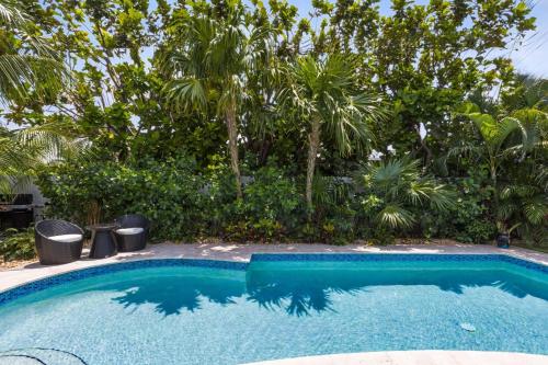 a swimming pool in a yard with palm trees at New! Luxurious Villa with Pool in West Palm Beach in Ibis Isle