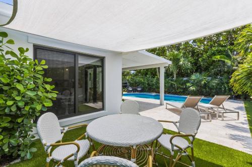 a patio with a table and chairs and a pool at New! Luxurious Villa with Pool in West Palm Beach in Ibis Isle