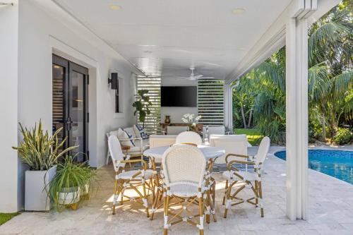a patio with a table and chairs and a pool at New! Luxurious Villa with Pool in West Palm Beach in Ibis Isle