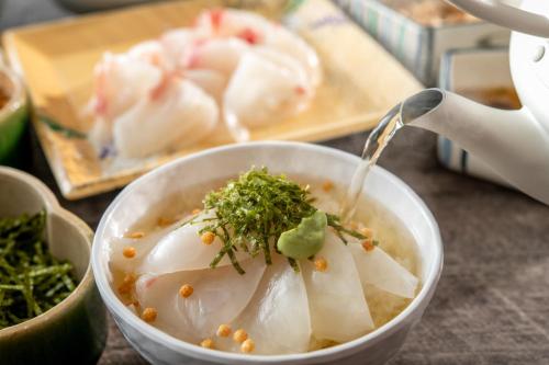 a person is pouring soup into a bowl of food at ART HOTEL Nippori Lungwood in Tokyo