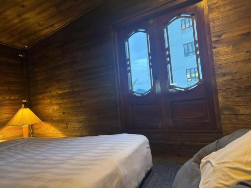 a bedroom with a bed and a lamp next to a window at Nhà Của Sen in Da Thien
