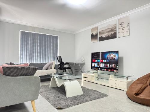a living room with a couch and a tv at Blissful Modern Home in Perth
