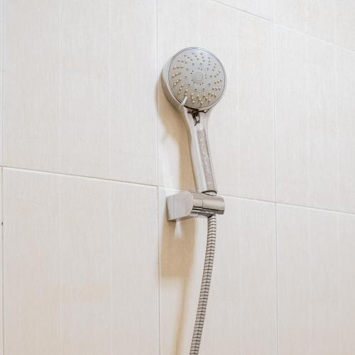 cabezal de ducha pegado a una pared de azulejos blancos en Chola Inn at Nagoya Hill Batam Mitra RedDoorz, en Jodoh