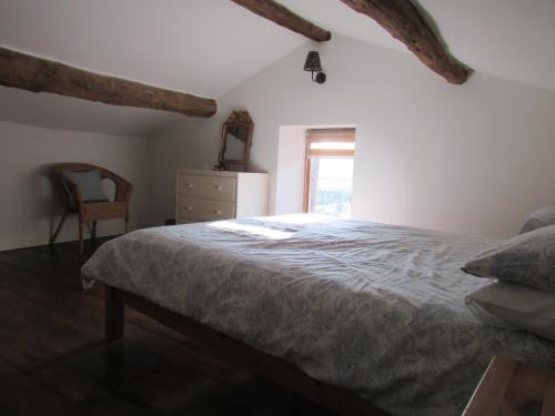 a bedroom with a bed and a chair and a window at Les Puvinieres in Breuil-Barret