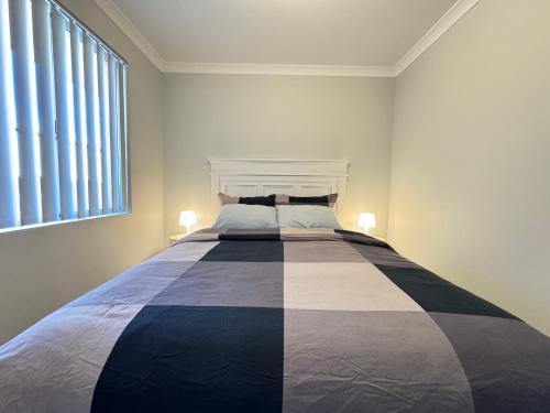 a large bed in a white room with two lamps at Blissful Modern Home in Perth