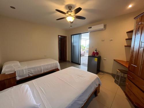 プエルト・バケリソ・モレノにあるOcean View Suite Cuencano's Houseのベッド2台と天井ファン付きの寝室