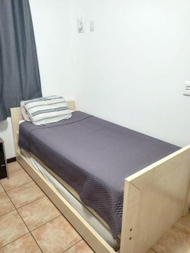 a bed in a room next to a wall at Casa térrea aconchegante in Blumenau
