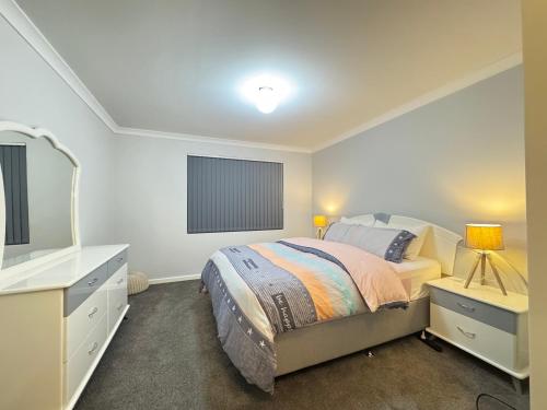 a bedroom with a bed and a dresser and a mirror at Blissful Modern Home in Perth