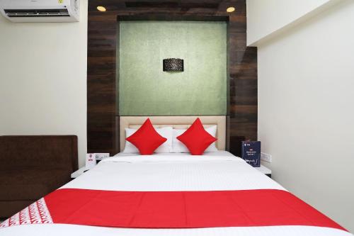 a bedroom with a white bed with red pillows at Super Hotel O ABIS INN Hotel Near Dhakuria Manipal Hospital in Kolkata