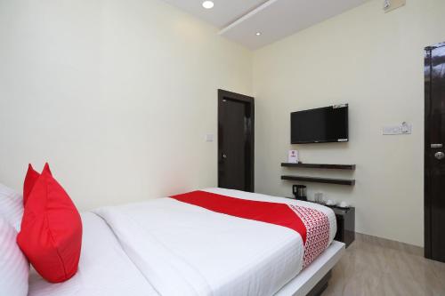 a bedroom with a bed with red pillows and a tv at Super Hotel O ABIS INN Hotel Near Dhakuria Manipal Hospital in Kolkata