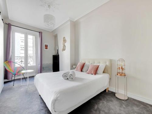 une chambre blanche avec un grand lit blanc avec des oreillers roses dans l'établissement Bright apartment - 2BR-4P - Belleville, à Paris