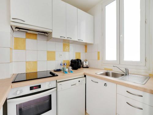une cuisine avec des armoires blanches et un évier dans l'établissement Bright apartment - 2BR-4P - Belleville, à Paris