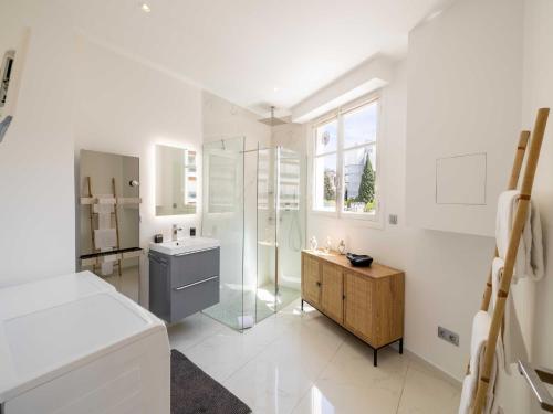 La salle de bains blanche est pourvue d'une douche en verre et d'un lavabo. dans l'établissement Modern apartment - 2BR-4P- Croisette plage, à Cannes