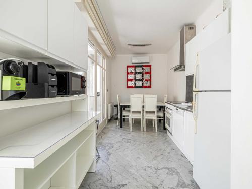 une cuisine avec des armoires blanches et une table avec des chaises dans l'établissement Modern apartment - 2BR-4P- Croisette plage, à Cannes