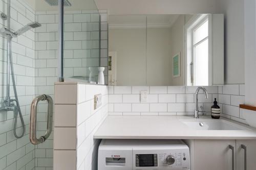 a white bathroom with a sink and a mirror at Kohimarama Beach 2 Bedroom Charmer in Auckland
